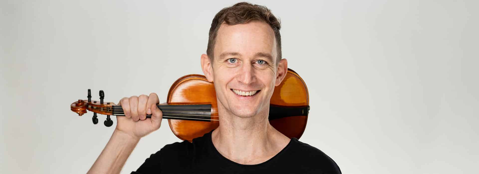 Andrew Fouts holding his violin behind his head