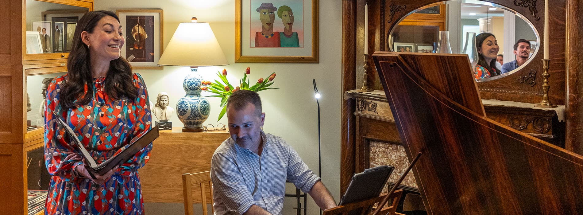 Woman singing and man playing piano in a home setting